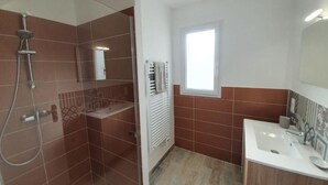 A bathroom with a shower, a sink, and a window.