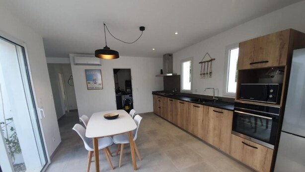 A modern kitchen with wooden cabinets, a dining table with chairs, and a built-in oven.