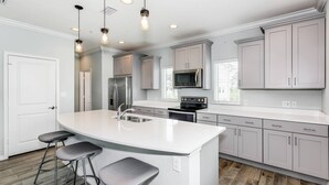 A modern kitchen with a central island, stainless steel appliances, and light-colored cabinetry.