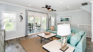 A spacious living room with a teal sofa, a coffee table, and a dining area with chairs.