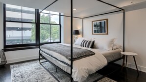 A four-poster bed with a view of the outdoors through large windows. - New Downtown Luxury Condo, by UNL, stadium & arena, above luxury retail #204 (Lincoln)
