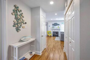 Enter a cozy living space with a fireplace, sofa, and chair, surrounded by a unique wall art piece and a console table.