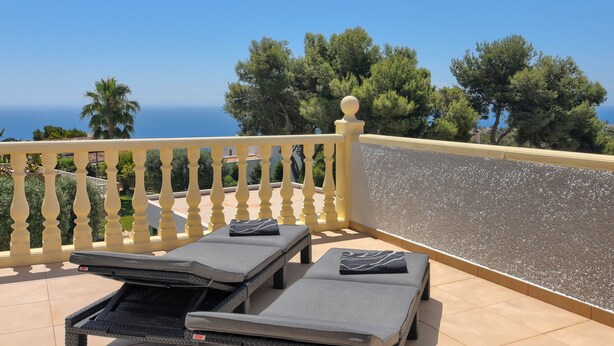 A balcony with two sun loungers, a balustrade, and a view of the sea and trees. - Wonderful and cheerful villa in Javea, Costa Blanca, Spain  with heated pool for 8 persons (Javea)