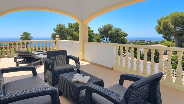 A covered outdoor seating area with wicker furniture and a view of the sea. - Wonderful and cheerful villa in Javea, Costa Blanca, Spain  with heated pool for 6 persons (Javea)