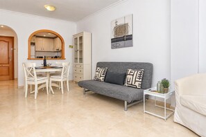 A living room with a grey sofa, white chairs, a small table, and a cabinet. - Beautiful and comfortable apartment in Javea, Costa Blanca, Spain  with communal pool for 2 persons (Javea)