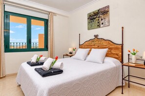 A hotel room with a bed, a nightstand, a window with curtains, and a painting on the wall. - Beautiful and comfortable apartment in Javea, Costa Blanca, Spain  with communal pool for 2 persons (Javea)