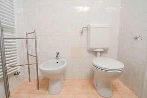 Une salle de bain équipée d’un bidet, de toilettes et d’un porte-serviettes.