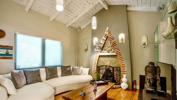Una sala de estar moderna con un sofá blanco, una mesa de centro de madera y una chimenea de ladrillo.