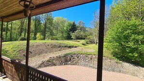Een overdekt buitengebied met uitzicht op een begrazend landschap en bomen.