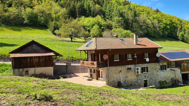 Een rustieke chalet met een stenen gevel, een balkon en een zonnepaneel op het dak.