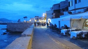 Una calle costera con mesas al aire libre y edificios a un lado.
