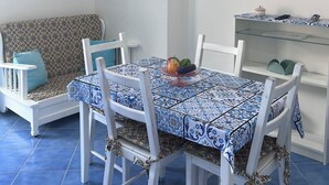 A dining area with a table set for four, a sofa, and a mounted flat-screen TV. - One-bedroom Apartment with Pool, Playground and breathtaking view (Piazza-Tralia-Pendolo)