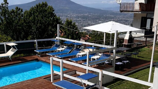 A swimming pool with a wooden deck, lounge chairs, and a view of a mountain. - One-bedroom Apartment with Pool, Playground and breathtaking view (Piazza-Tralia-Pendolo)
