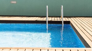 A rectangular swimming pool with two metal ladders on one side, surrounded by a wooden deck. - CASA NINA - Charming apartment with pool on the property (Porto)