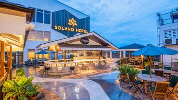The Solano Hotel's outdoor area with a bar, seating, and potted plants.