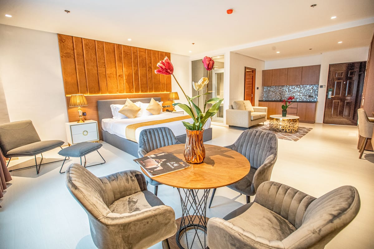 A modern hotel room with a bed, seating area, and a dining table.