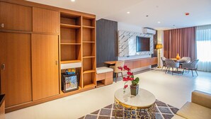 Ein modernes Wohnzimmer mit einer Couch, einem Couchtisch, einem an der Wand befestigten Fernseher und einem Essbereich mit Stühlen.