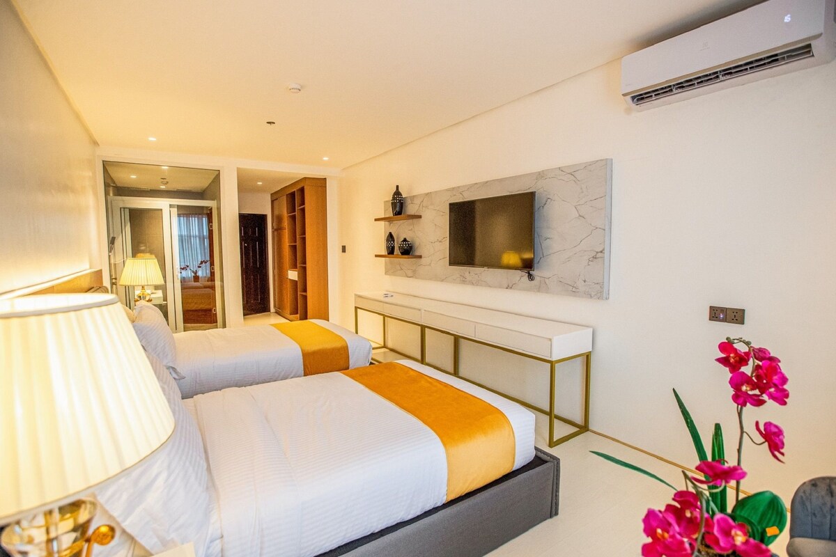Une chambre d’hôtel avec deux lits, un téléviseur fixé au mur, un bureau et une chaise.