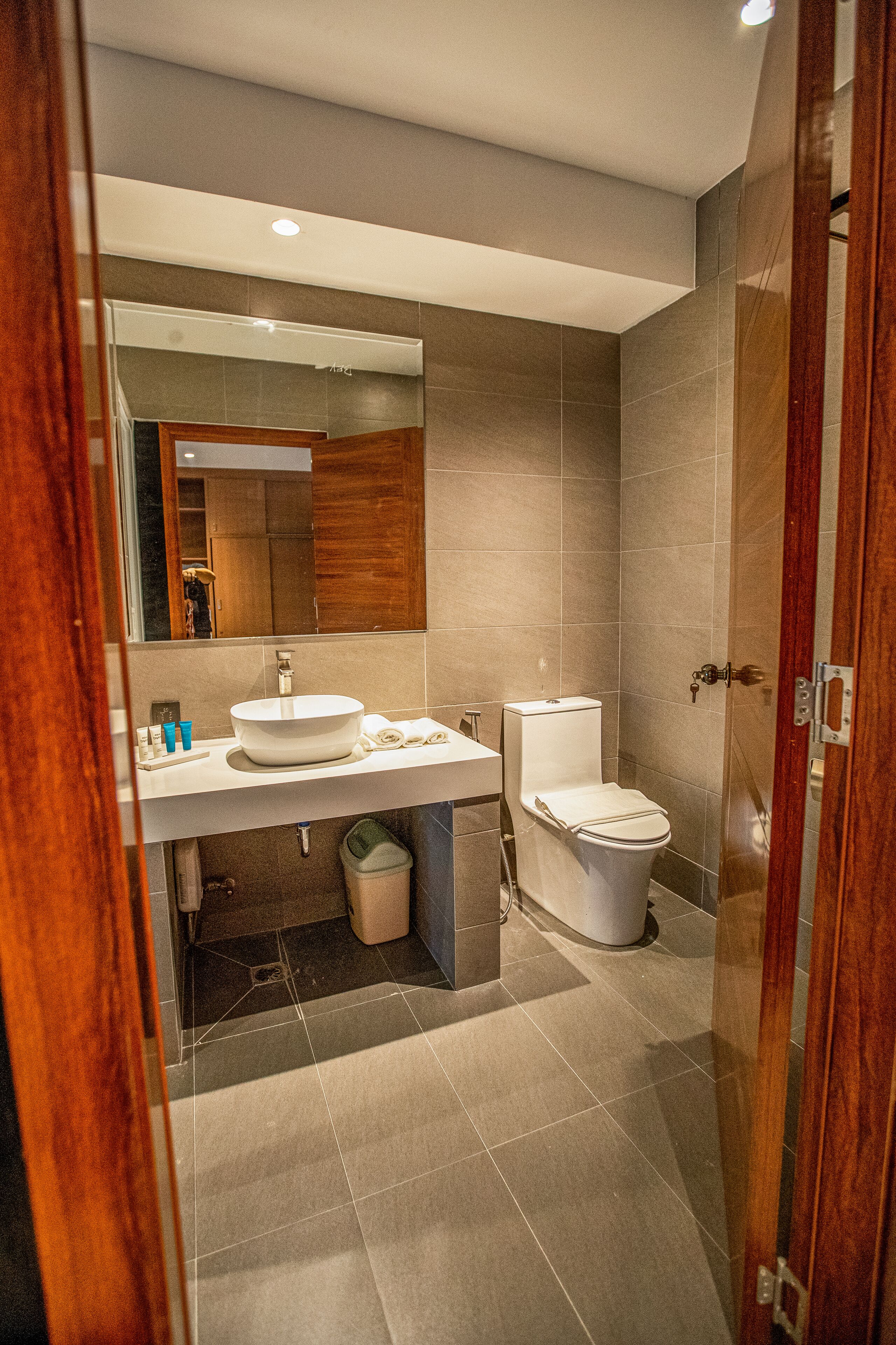 Een moderne badkamer met een grote spiegel, een wastafel, toilet en een douchegedeelte.