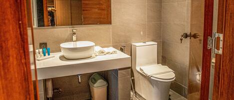 A modern bathroom with a large mirror, a sink, a toilet, and a shower area.