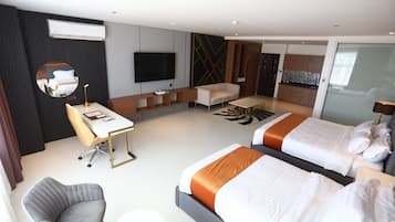 A modern hotel room with a large bed, a desk, a chair, a TV, and a kitchenette.