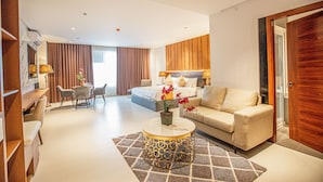 Ein modernes Hotelzimmer mit Bett, einer Couch, einem Essbereich und einem Couchtisch.