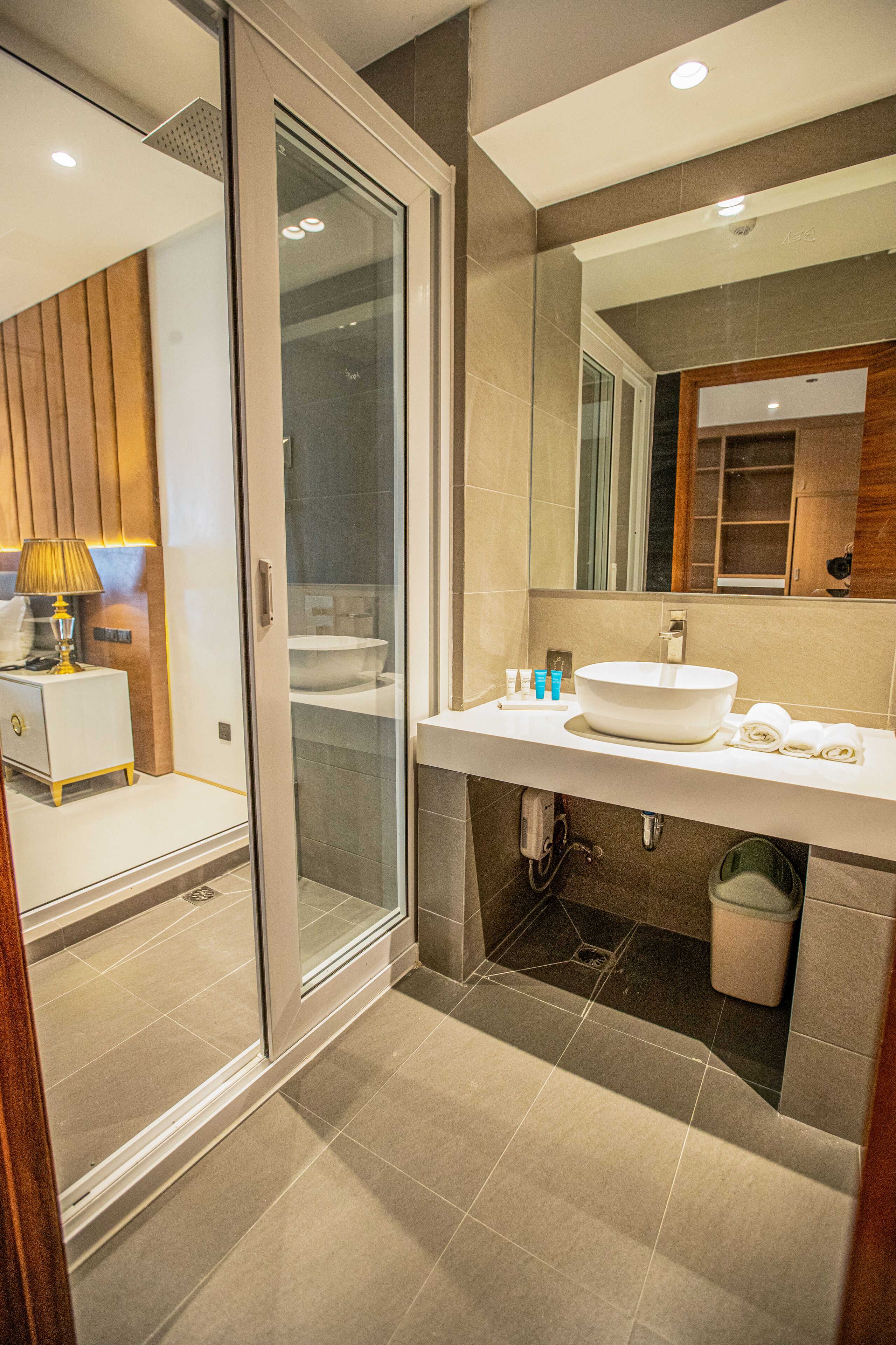 A modern bathroom with a glass shower enclosure, a large sink, and a mirror above it.