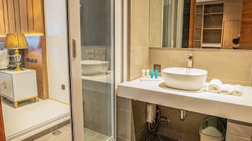 Un baño moderno con cabina de ducha de vidrio, un lavamanos grande y un espejo sobre él.