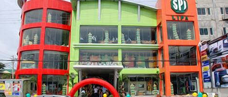 Un immeuble à plusieurs étages, doté d’une façade verte et rouge, avec une grande vitrine et un panneau bien visible portant l’inscription « SPJ ».