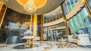 Eine Hotelhalle mit einer Rezeption, einem Chandelier, einer Couch und einer großen Glaswand.
