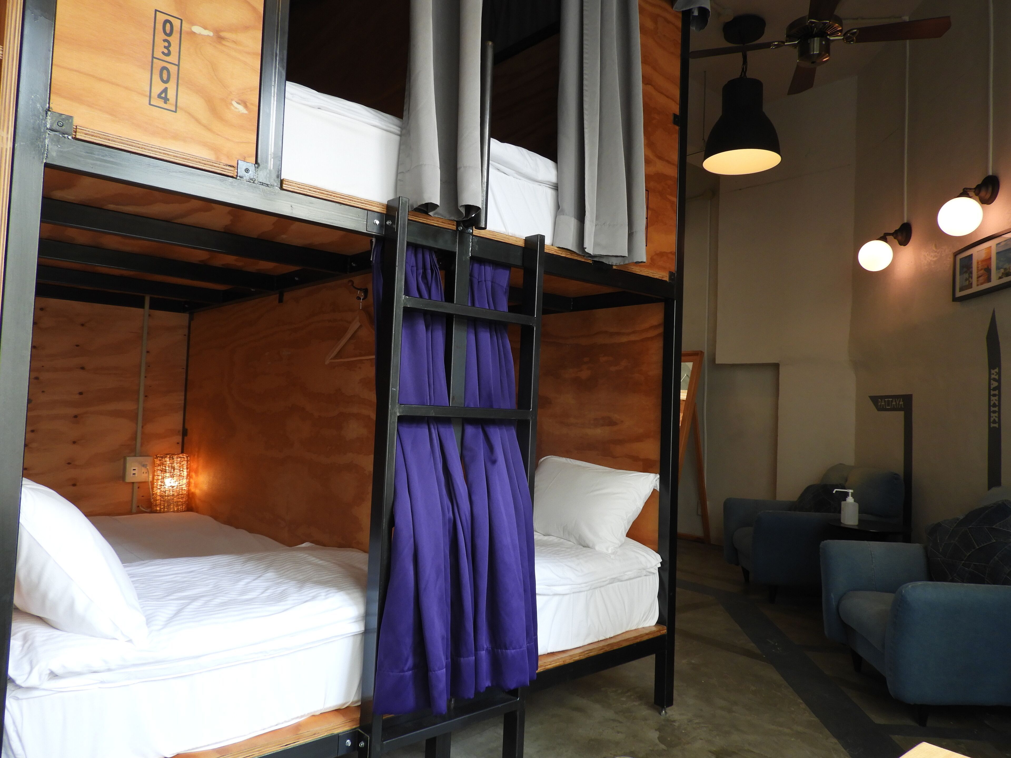 A bunk bed room with a wooden headboard, a purple curtain, and a white mattress.