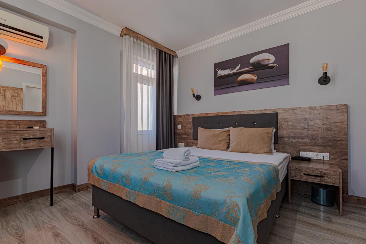 Una camera da letto con un letto, un comodino, una cassettiera, un condizionatore d'aria, una finestra con tende e un'opera d'arte appesa al muro.