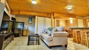 A cozy living room with a wooden ceiling, a sofa, a coffee table, a TV, and a fireplace.