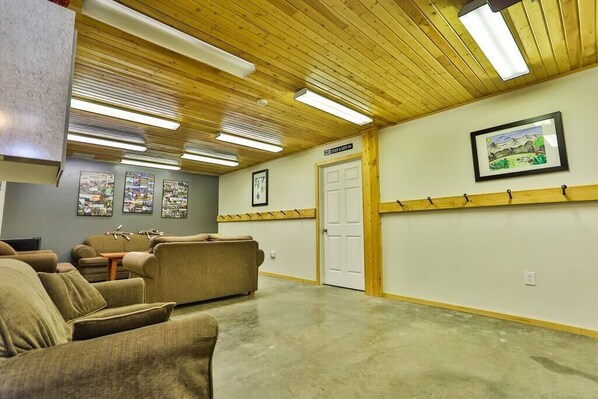 A spacious room with wooden ceiling and walls, a door, and a framed picture on the wall.