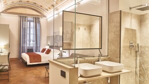 A modern hotel room with a large bed, a glass-enclosed shower, and a large mirror.