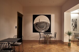 Zona pranzo con tavolo e sedie, un'ampia opera d'arte incorniciata a parete e una pianta in vaso.