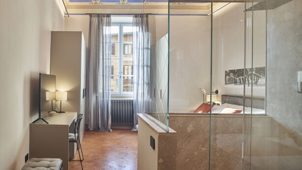 A modern bathroom with a glass shower enclosure, a vanity with a mirror, and a radiator near the window.