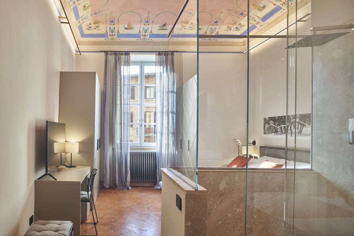 A modern bathroom with a glass shower enclosure, a vanity with a mirror, and a radiator near the window.