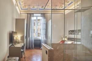 Un bagno moderno con box doccia in vetro, un mobile vanitario con specchio e un termosifone vicino alla finestra.