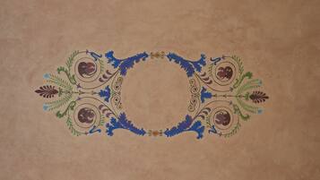 Una moldura decorativa con patrones florales y de hojas simétricos en una pared con textura.