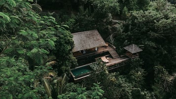 A secluded resort with a pool, wooden deck, and a staircase leading to a wooden structure.