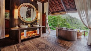 A wooden bathroom with a large mirror, a sink, and a bathtub. - Buahan, A Banyan Tree Escape (Payangan)
