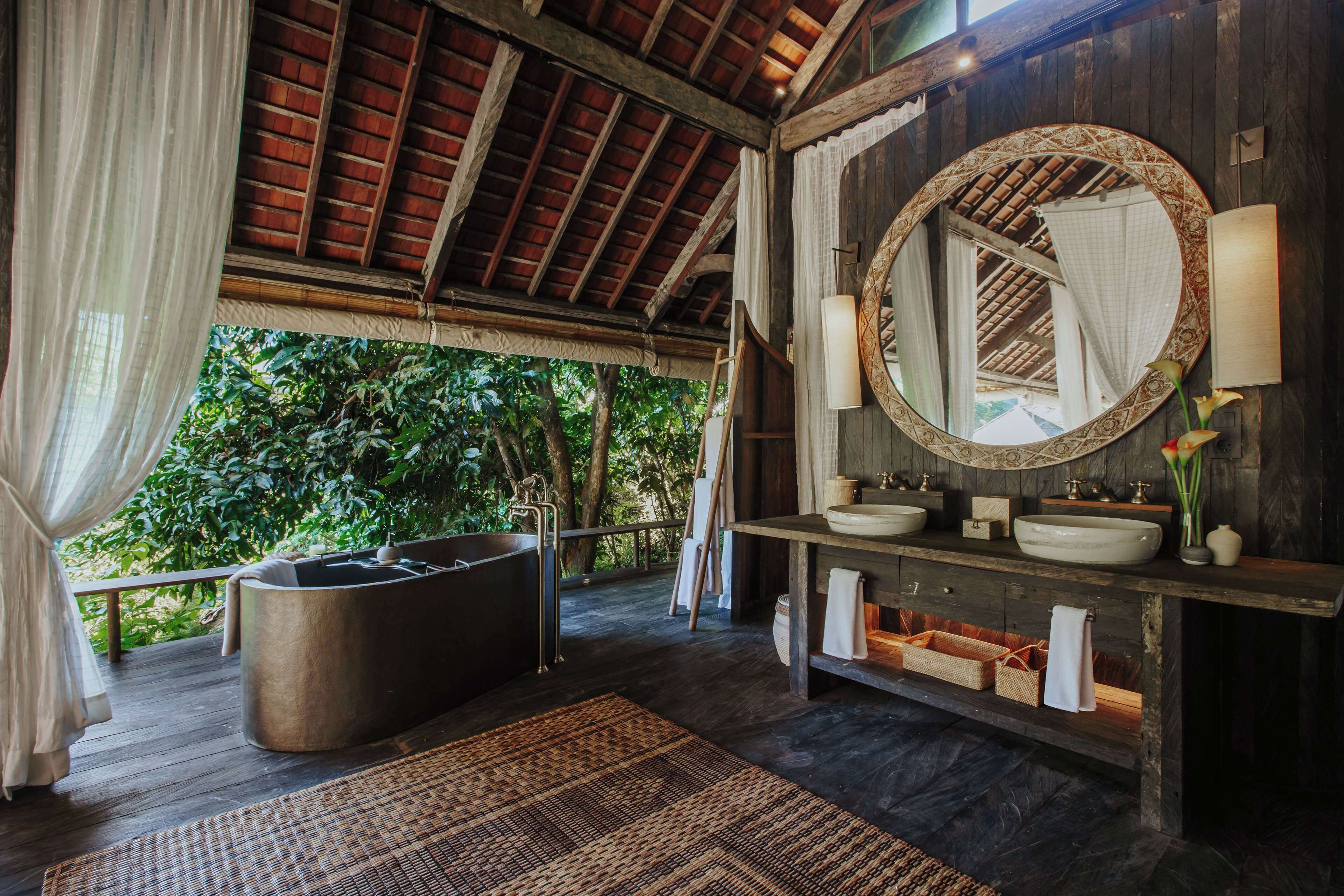 Un baño con bañera, espejo redondo y tocador de madera.