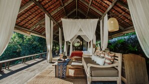 A wooden deck with a canopy bed, a bench, and a hanging light fixture. - Buahan, A Banyan Tree Escape (Payangan)