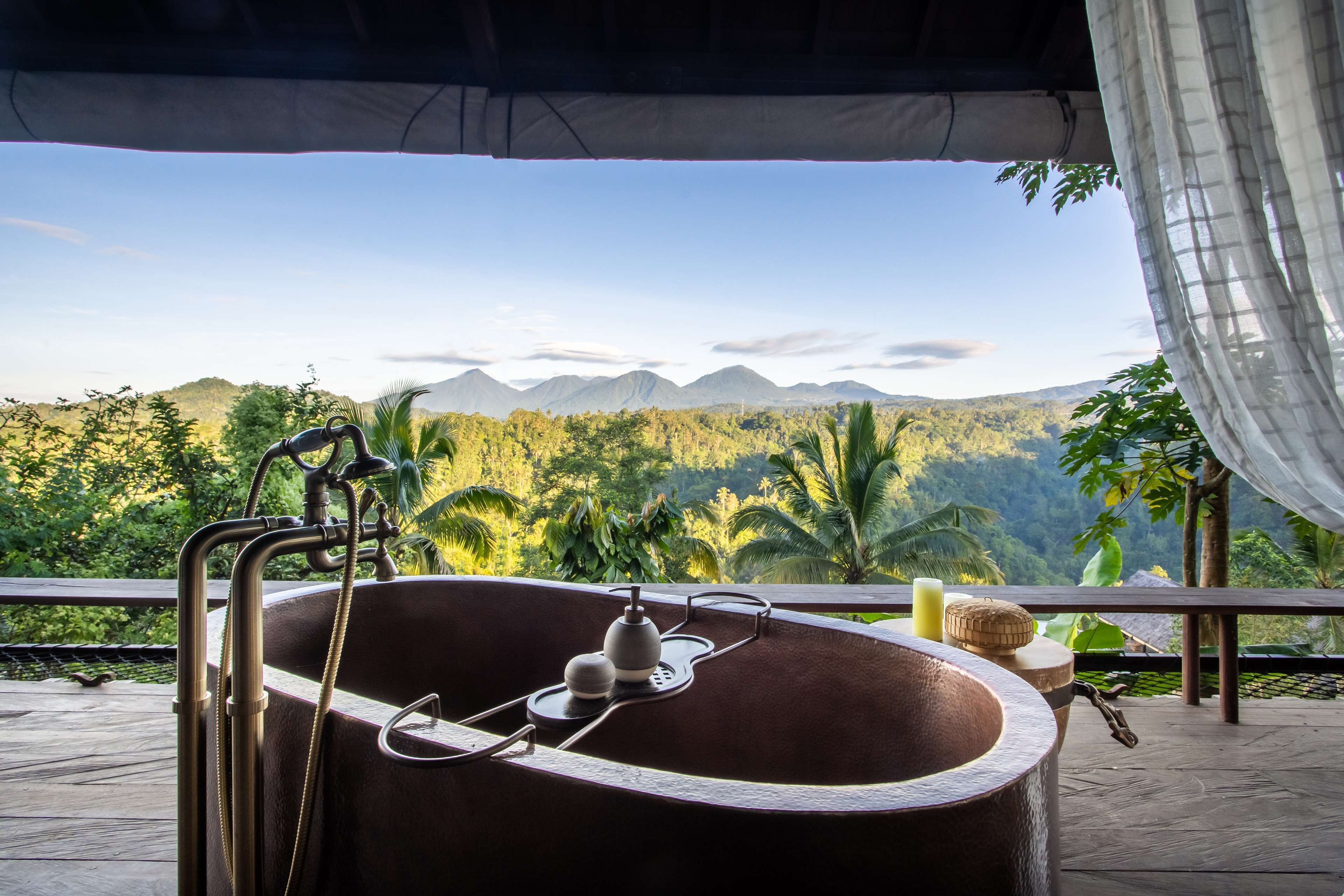 A bathtub with a view of mountains and greenery.