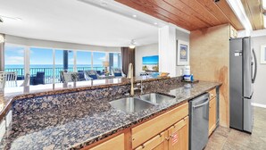 A kitchen with granite countertops, stainless steel appliances, and wooden cabinets. - Private Balcony~ Pool~Grills~3BR Long Beach Resort #2-201 (Panama City Beach)