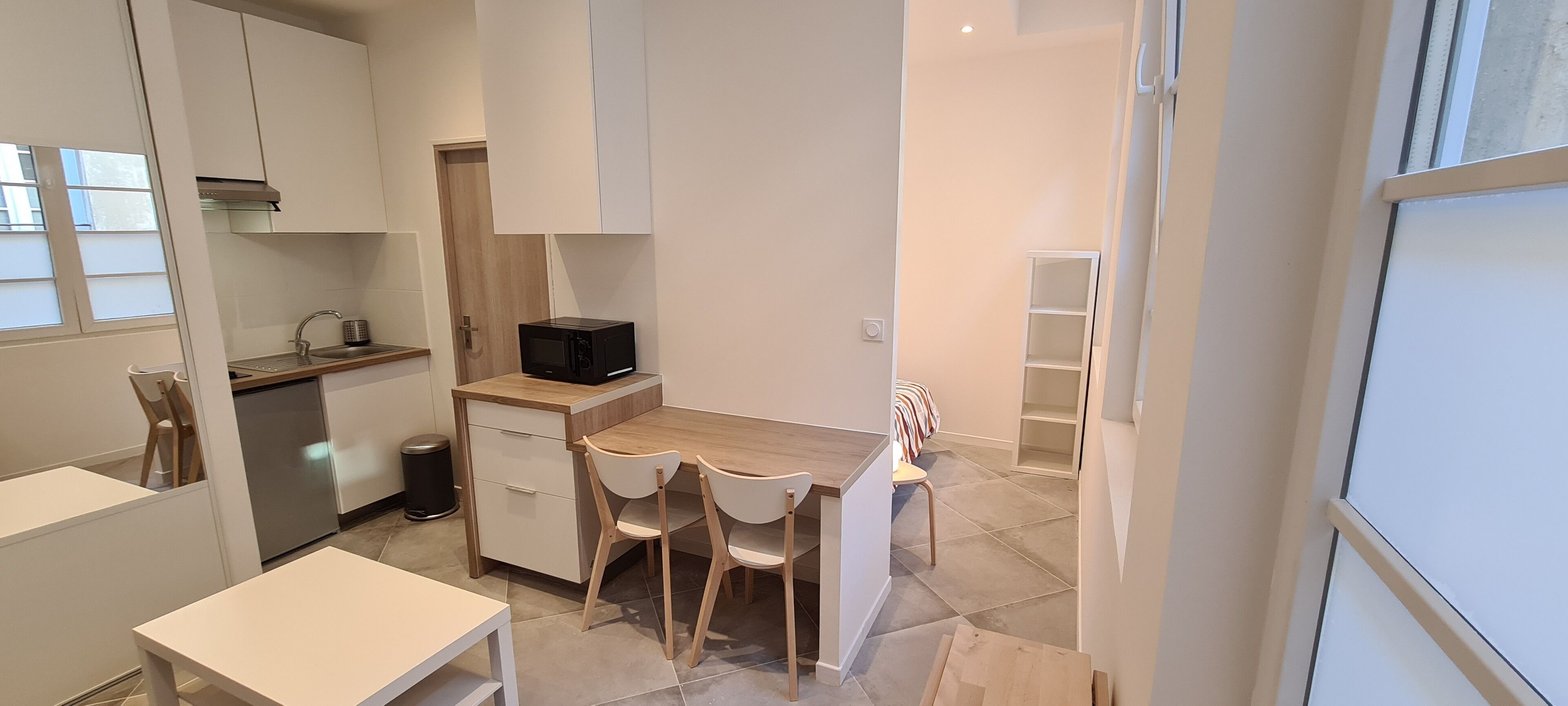 A compact kitchen with a microwave, a sink, and a small dining area with chairs and a table.