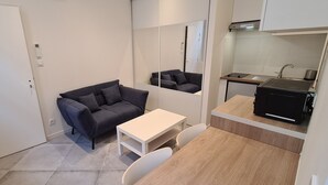 Une cuisine compacte avec un coin repas, comprenant un canapé, une table et un petit comptoir avec une cuisinière.