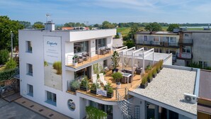 A modern apartment building with a rooftop terrace featuring outdoor furniture and plants. - Elegante Apartments - Adults only (Wladyslawowo)