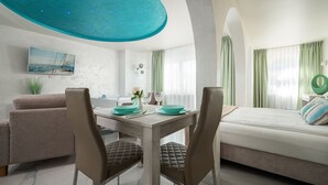 A modern hotel room with a dining area, a bed with a view, and a ceiling light fixture. - Elegante Apartments - Adults only (Wladyslawowo)